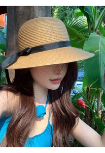 Detailed texture of the khaki straw hat weaving with a decorative black ribbon bow