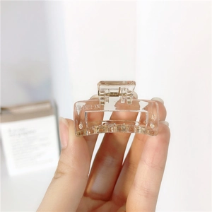 Detail showing a transparent square hair claw clip with a strong metal spring mechanism