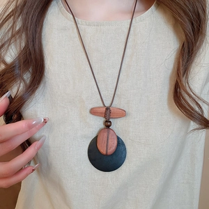 Close-up of minimalist wooden shell pendant necklace worn over a beige linen shirt