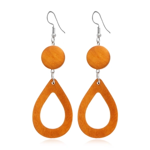 Détail de boucles d'oreilles pendantes en bois avec texture géométrique orange brun