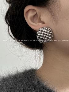 Detailed view of silver hollow beaded spherical earrings worn by a fashion model