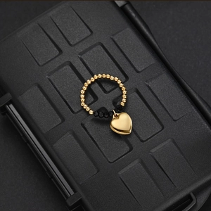 Detail of beaded elastic ring with gold beads, black faceted beads and heart pendant