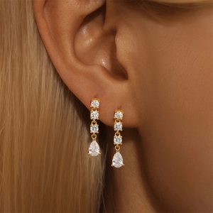 Close-up of dangling gold-tone drop earrings with sparkling white cubic zirconia gems