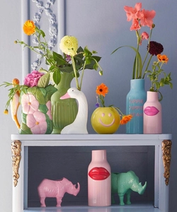 Close-up of creative ceramic vases in pastel colors on an elegant purple display cabinet