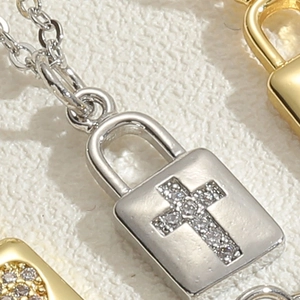 Macro detail of silver lock pendant with zircon cross on a white stone base