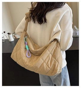 Detail of khaki quilted tote bag featuring knot shoulder strap and decorative colorful cords