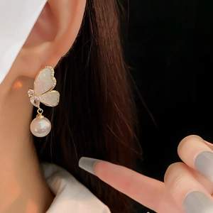Macro view of butterfly earring featuring sparkling diamonds and elegant pearl tassels