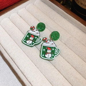 Macro shot of green glitter cup earrings with snowman and candy cane festive details