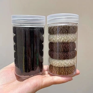 Close-up of thick elastic hair ties set in plastic jars with black and coffee tones