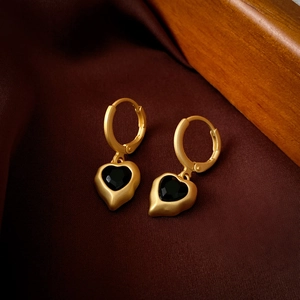 Detail view of vintage heart earrings with black stone on dark silk fabric