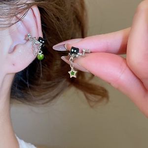 Detail of silver star ear cuff with green pendant shown on ear and held by hand