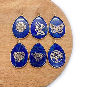 Lapis lazuli teardrop pendants with gold filigree animal patterns on wooden base