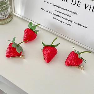 Realistic red strawberry hair clips with green leaves and gold duckbill base from four angles