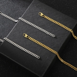 Polished gold and silver stainless steel Cuban link necklaces on a textured black stand