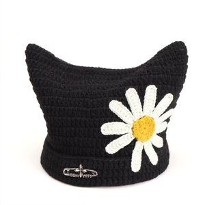 Detail of black cat ear beanie with white daisy patch and silver cross safety pin
