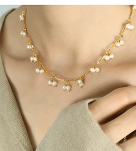 Close-up detail of a delicate gold chain necklace with small white freshwater pearls