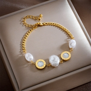 Detail of gold chain bracelet featuring Baroque pearls and engraved Roman numeral charms