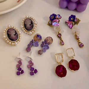 Flat lay of vintage style purple pearl earrings with gold accents and crystal pendants