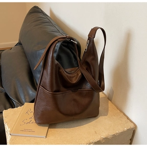 Detailed view of the dark brown leather bucket bag on a minimalist stone pedestal