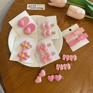 Close-up of pink hair clip set with hearts and flowers in a white ceramic dish