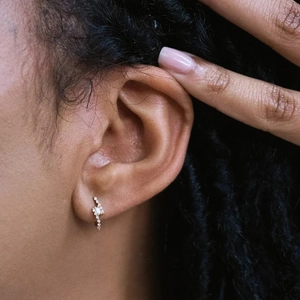 Macro shot of S925 silver lightning earring with small diamonds on female ear