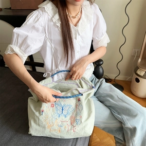 Détail du sac fourre-tout oxford vert clair avec broderie papillon bleu et anse en corde