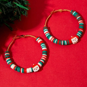 Macro view of Christmas wreath hoop earrings with Santa charms on red festive background