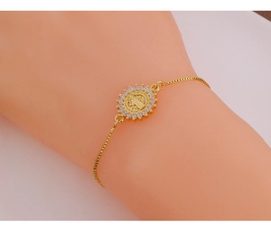 Close-up of gold Saint Benedict medal bracelet with zircon inlay on model wrist
