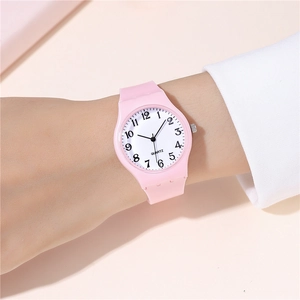 Close-up of pink silicone watch on wrist with minimalist numeric dial and quartz movement