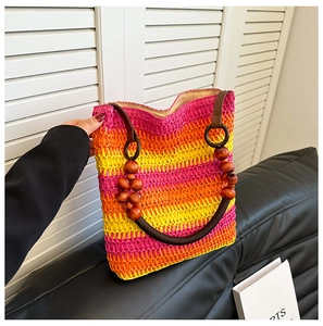 Close-up of rainbow gradient straw beach bag featuring decorative wooden beads on the handle