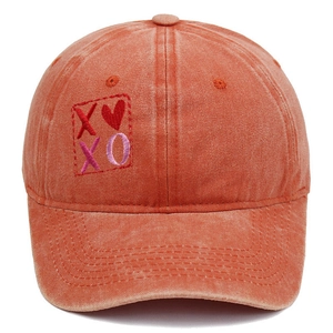 Dettaglio del ricamo a cuore XOXO sul cappellino da baseball in tela lavata arancione