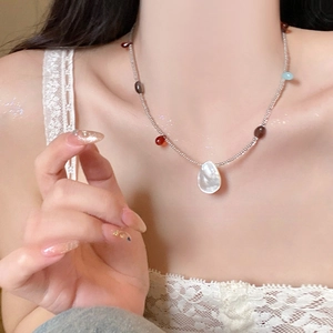 Detailed view of colorful beaded necklace with a white pearlescent teardrop pendant