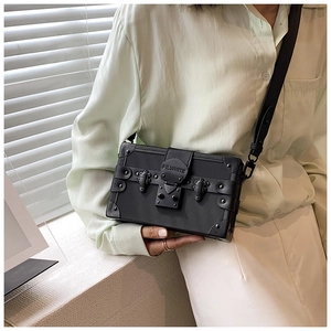 Detail view of a black box shoulder bag with silver studs and metal clasp on a model