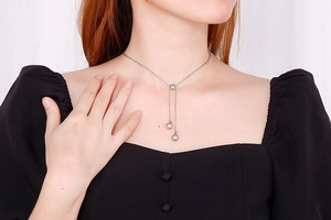 Detail of silver Y-shaped stainless steel necklace with ball pendants on a model