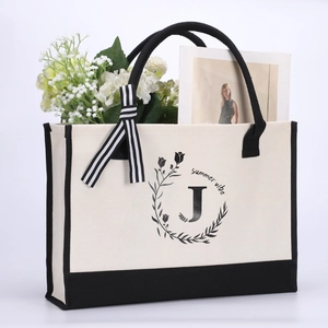 Detail of canvas tote bag with letter J embroidery and ribbon on handle with flowers