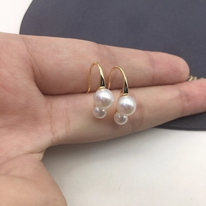 Detailed view of gold hook earring with classic large and small white freshwater pearls