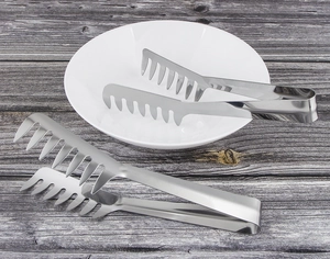 Macro shot of two stainless steel spaghetti tongs with comb heads on a dark wood background