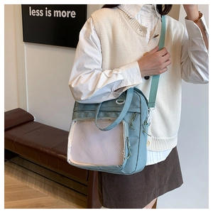 Detail of light blue crossbody bag featuring a transparent mesh front display pocket