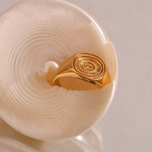 Detailed view of an 18K gold plated fingerprint signet ring inside a spiral seashell