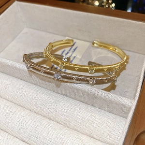 Detail of gold and silver plated open bangles with brushed texture and inlaid crystals