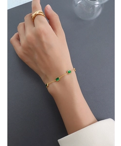 Détail d'un bracelet doré 18K avec zircons carrés vert émeraude porté par un mannequin