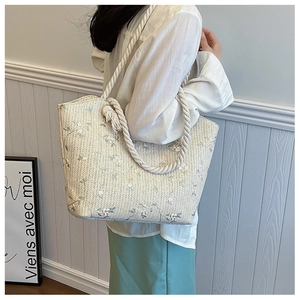 Détail du sac cabas en paille avec broderie florale et anses en corde de coton blanc