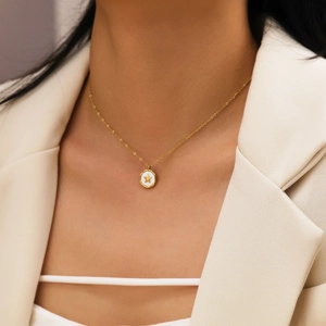 Elegant gold star necklace with round white pendant worn on model with beige suit