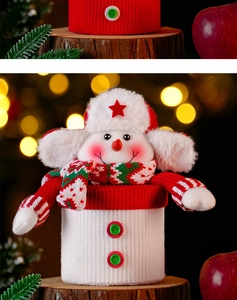 Close-up of knit snowman Christmas candy jar with festive scarf on a wooden base