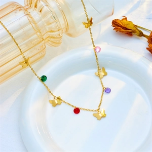 Goldene Schmetterlingskette mit bunten Edelsteinperlen auf einem weißen Teller