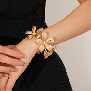 Detailansicht eines goldfarbenen Blumenarmbands mit Kristallbesatz am Handgelenk