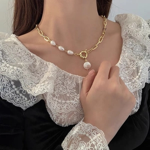 Detailed view of French vintage necklace with golden metal chain and baroque pearls