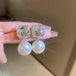 Macro shot of oversized square crystal and round pearl earrings with starburst sparkle
