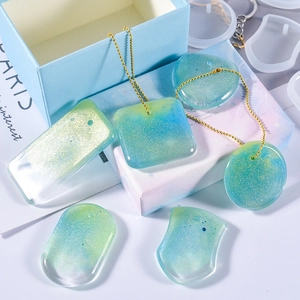 Macro view of silicone molds with finished glitter resin pendants in various shapes