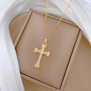 Elegant gold titanium cross necklace with sparkling crystals on a jewelry box